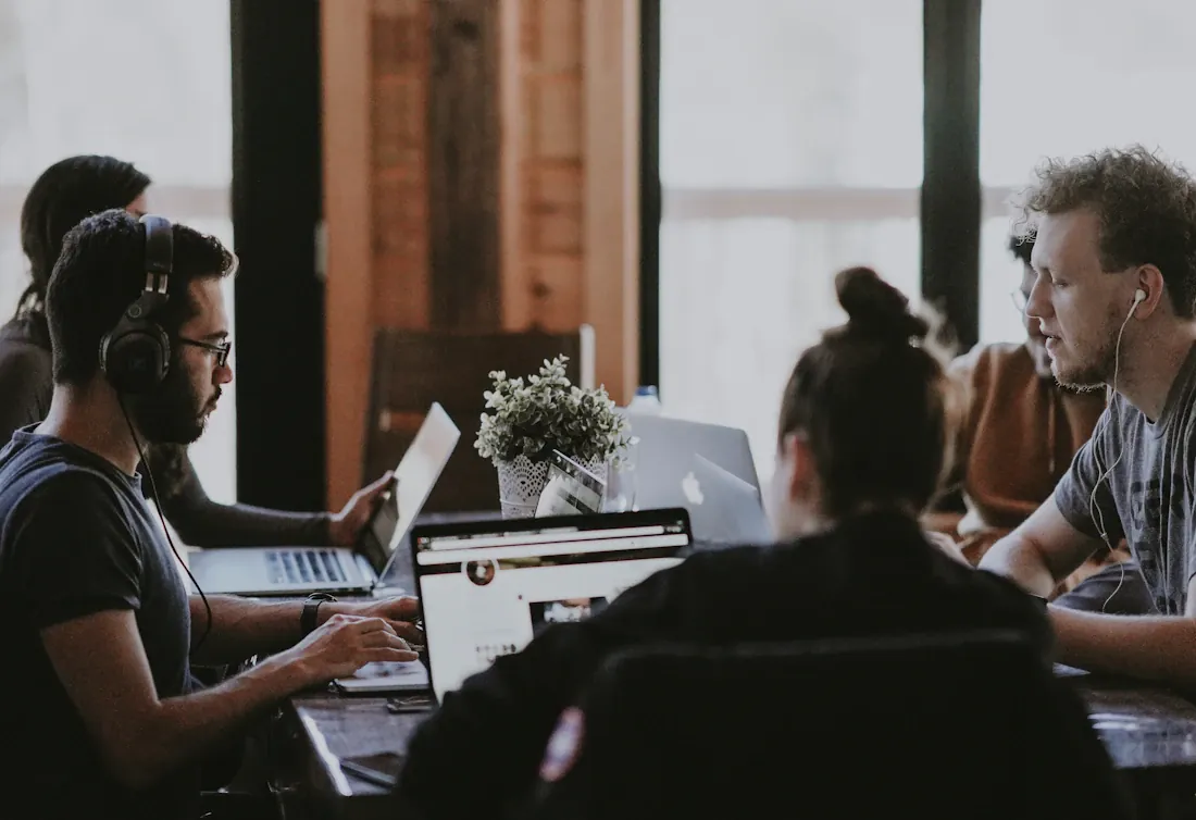 Équipe échangeant autour d’ordinateurs portables dans un bureau partagé.